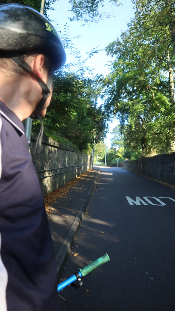 Cyclist looking along the road, that is going uphill at the start of a climb.