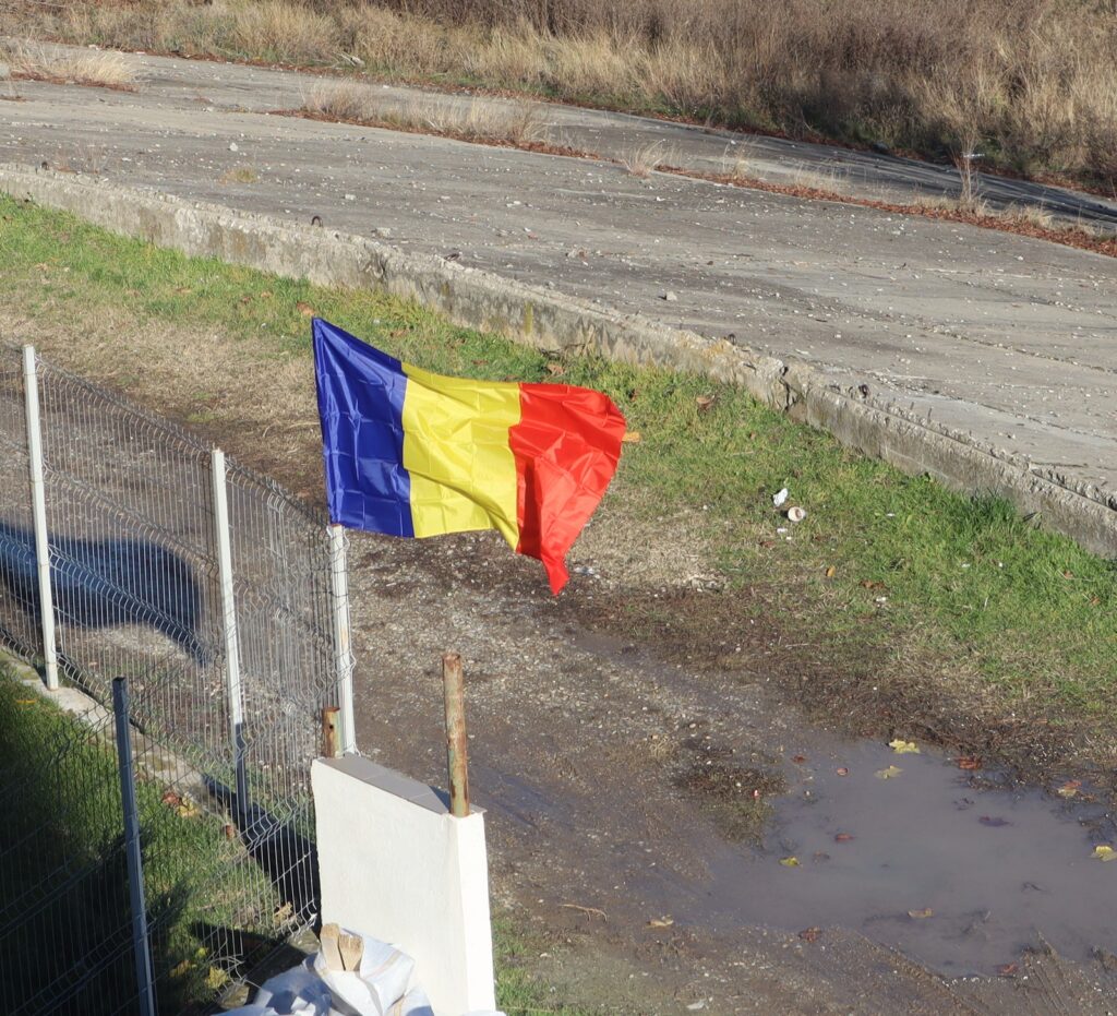 A Romanian flag flies on a fence post.